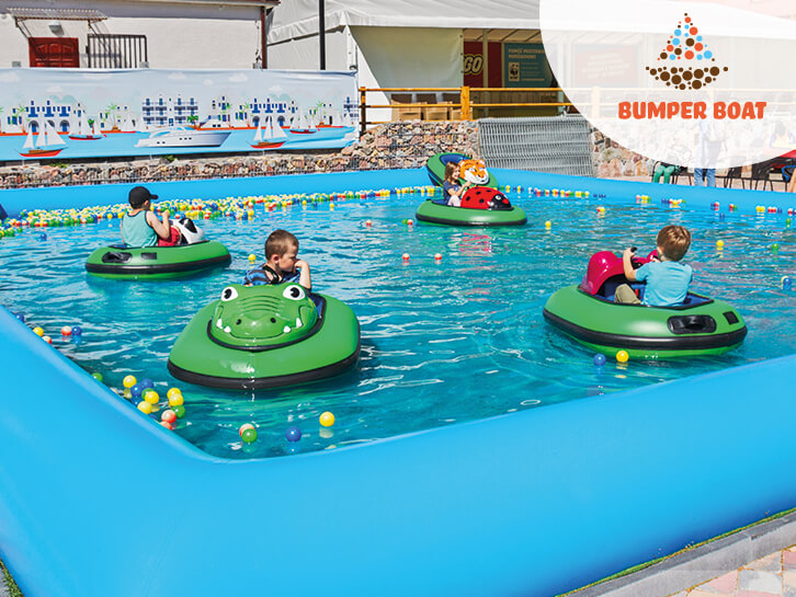 Radosne dzieci pływają na łódeczkach Bumper Boat w basenie wypełnionym wodą i kuleczkami