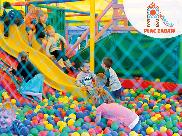 Uśmiechnięte Dzieci zjeżdżają ze zjeżdżalni do basenu wypełnionego kolorowymi piłeczkami na Placu Zabaw Discovery Park