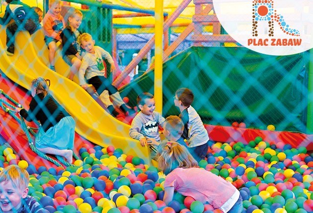 Uśmiechnięte Dzieci zjeżdżają ze zjeżdżalni do basenu wypełnionego kolorowymi piłeczkami na Placu Zabaw Discovery Park