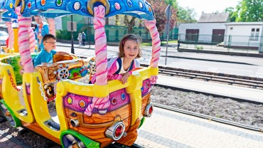 Zadowolone dzieci jadą kolejką w Parku Rozrywki